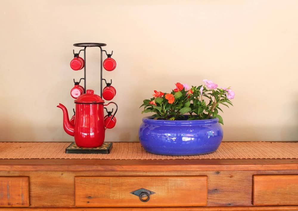um jarro de flores e uma cafeteira com xícaras em cima de uma mesa de madeira